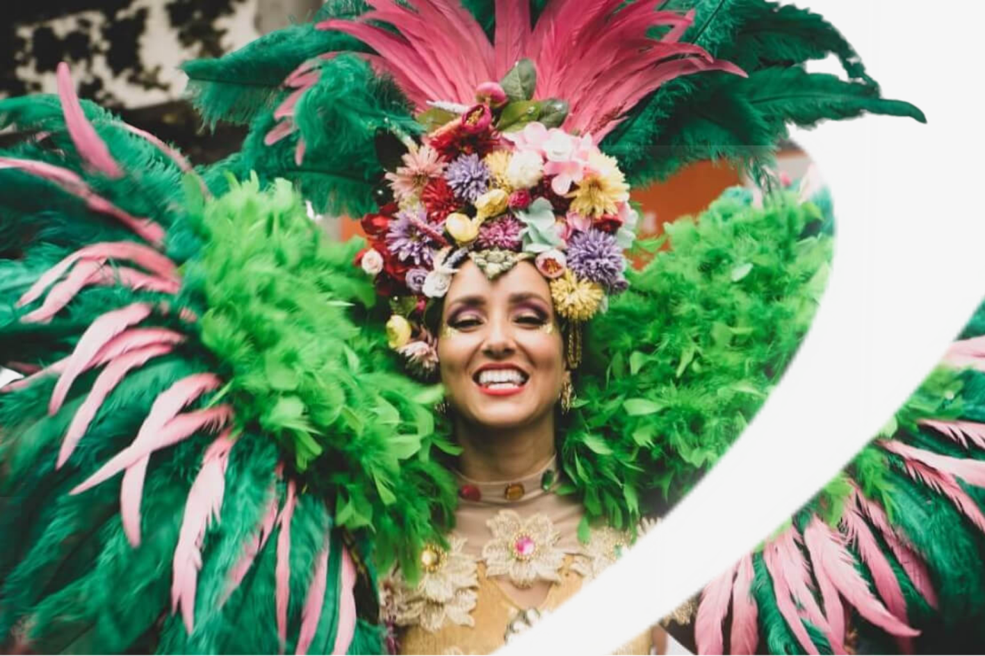 A woman wearing green feather carnival dress smiling at the camera